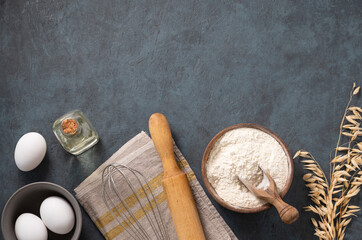 Oatmeal in a wooden bowl with eggs, rolling pin and oli on a dark blue background. Natural organic...