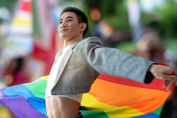 Young man waving LGBT rainbow flag celebrate pride month on colorful blur background, human rights and Lgbtq community concept