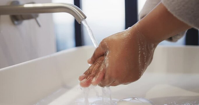 Close up african american plus size woman washing hands in bathroom, slow motion