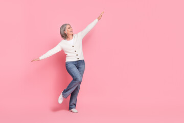 Full body photo of gorgeous mature grandma hands wings plane fly have fun wear trendy white outfit isolated on pink color background