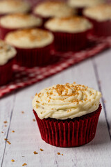 red velvet cupcake with icing and gold sprinkles on a white table