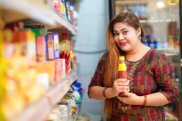Indian woman purchasing sauce at grocery shop.