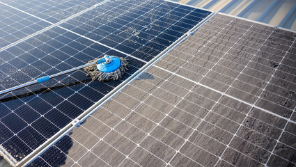 Technican using a mop and water to clean the solar panels that are dirty with dust and birds'...
