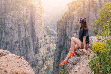 Obraz premium Happy traveler girl sitting on top of the Tazi canyon in Turkey. Tourist attractions and destinations