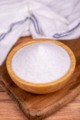 Natural minaret crystal non-iodized grinding salt on wooden background. Ground rock salt in wooden bowl