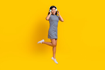 Fototapeta na wymiar Full body length photo of korean beautiful girl new sony headphones quality music jumping wear striped dress isolated on yellow background