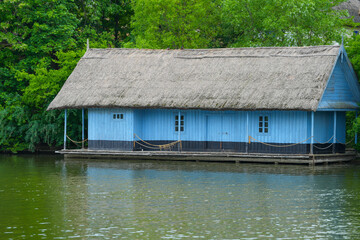 Fototapeta na wymiar the old wooden house with a reed roof at the edge of the lake.