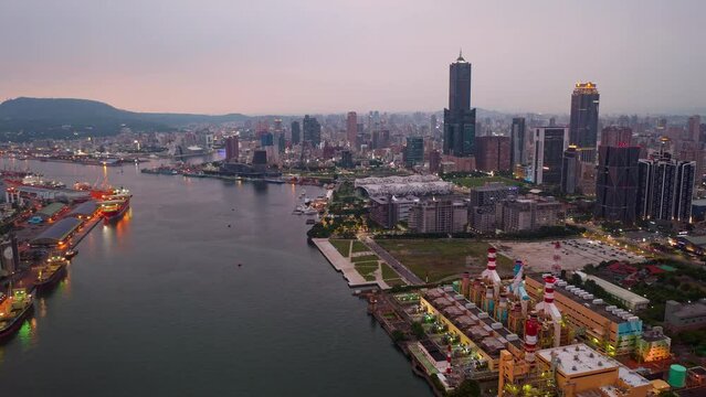 Aerial hyperlapse of Kaohsiung, a vibrant seaport city in Southern Taiwan, with 85 SKy Tower standing out in downtown next to the harbor and city lights begining to glow at nigthfall in rush hour