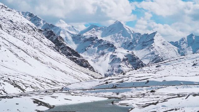 Lake in front of the snow covered Himalayan mountain peaks at Shinkula Pass on the way to Zanskar at Himachal Pradesh, India. High altitude lake covered by snow and surrounded by snowy Himalayas. 