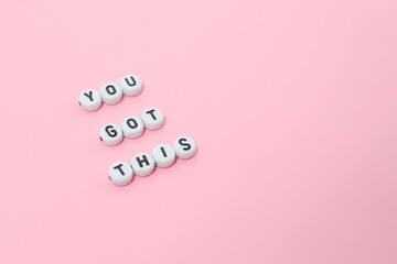 Top view of "you got this" quotes made out of beads on pastel background. motivation and success concept