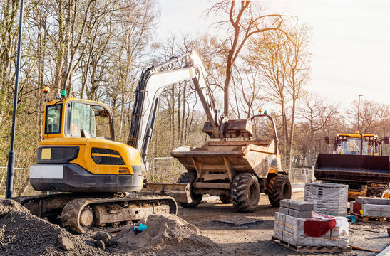 Excavator loading semi-dry concrete mix into dumper on construction site