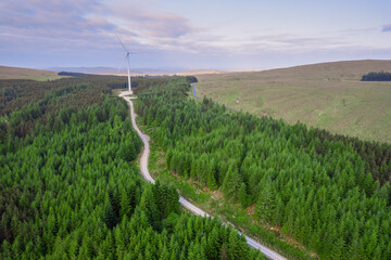 Aerial view on a wind farm turbine build in a rural country area with green forest. Making power...