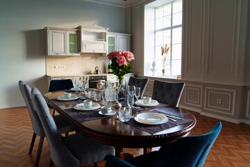 table with dishes and bouquet of roses in the bright kitchen of the living room 