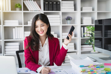 Young happy businesswoman talking on cellphone make notes and using laptop computer working online in modern office. Entrepreneurship And Business Career, Distance Freelance Job Concept.