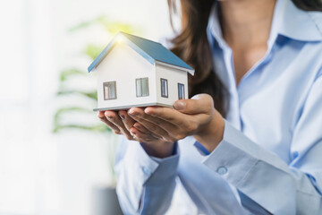 Businesswoman holding a house model .House on Hand with piggy bank.Real estate,Property insurance and security concept.Savings and finance concept.