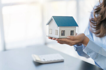 Businesswoman holding a house model .Real estate,Property insurance and security concept.Savings and finance concept.