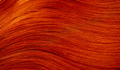 Red hair close-up as a background. Women's long orange hair. Beautifully styled wavy shiny curls....