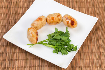 Baked thick short sausages with greens on the square dish