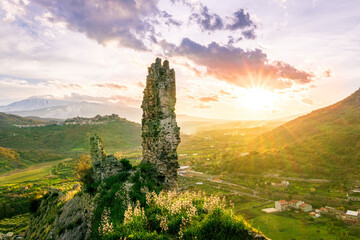 beautiful medieval castle ruins on mountain during nice sunset or sunrise with highland landscape...