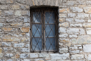 Barred window and fragment of stone wall of mediaeval building