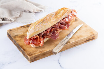 Spanish serrano ham sandwich on white marble background