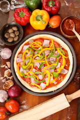 Homemade Italian pizza, mixed vegetables, cheese and bacon, fresh out of the oven. Placed on a dark wooden floor. Top view. Fast food concept.