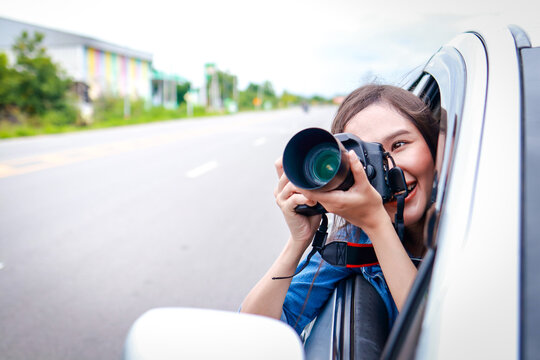 Beautiful Asian woman traveling in private car holding camera. Transport concept, tourism. Asian tourists. copy space