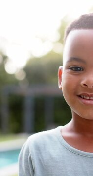 Vertical video portrait of happy african american boy smiling in sunny garden, slow motion