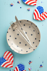 Obraz premium Get ready to celebrate Independence Day in style! Vertical top-down view of table set for occasion, featuring plate, silverware, festive decorations like American flag-patterned hearts and confetti
