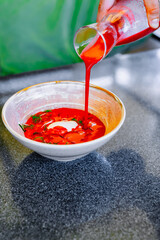 waiter pours cold beetroot soup into plate