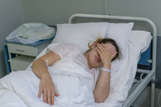 A woman with having contractions, lying on a hospital bed, waiting for a caesarean section. Photo concept with selective focus.