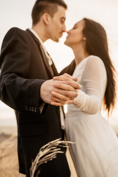 Pareja joven de novios recien casados celebrando su boda informal con una sesion de fotos al atardecer en el campo, muestran sus alianzas
