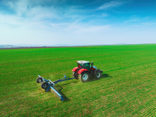 Tractor with a roller tillage on spring field. Aerial view of Soil rolling supports germination and...