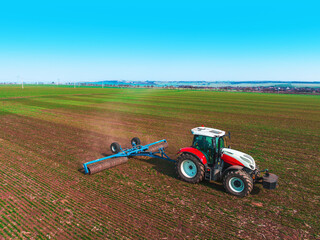 Tractor on agricultural field. Aerial view of Soil rolling agronomy tractor.
