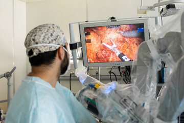 A laparoscopic surgeon at work, performing a minimally invasive surgery, using a robot-assisted,...