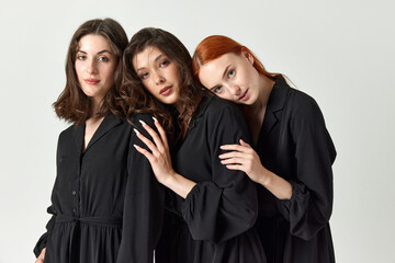 Support and friendship. Portrait of young, tender, beautiful young women in black dresses against light studio background. Concept of elegant fashion, female beauty, business, shopping, sales, ad