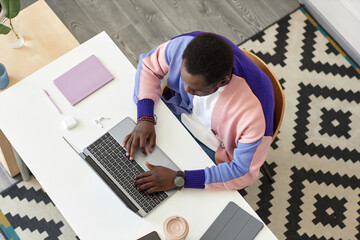 Top view at black man working with laptop in creative office interior, copy space