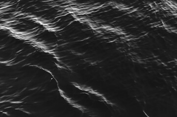 Black water surface with waves. Water ripples. Texture of the water surface.