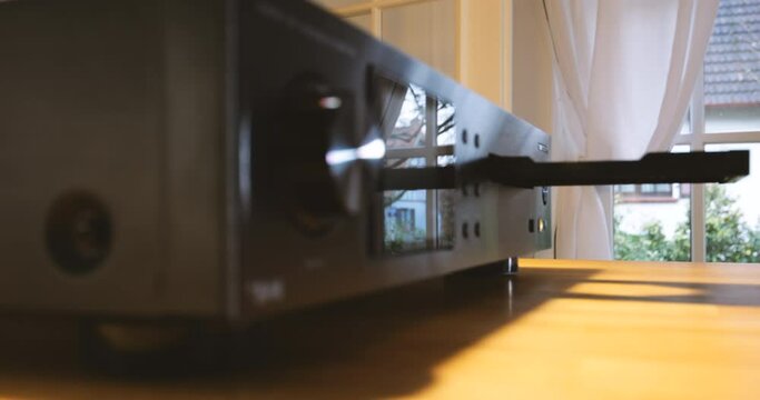 Hand inserts a CD into hi-fi system. Audiophiles love clear sound from loudspeaker streaming FLAC, MP3, & MQA files. Enjoy music in vintage stereo - time-lapse fast motion