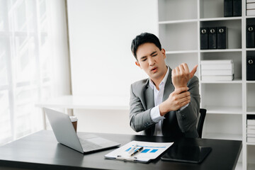 Overworked young Asian businesswoman office worker suffering from neck pain after had a long day at office desk. office syndrome concept..