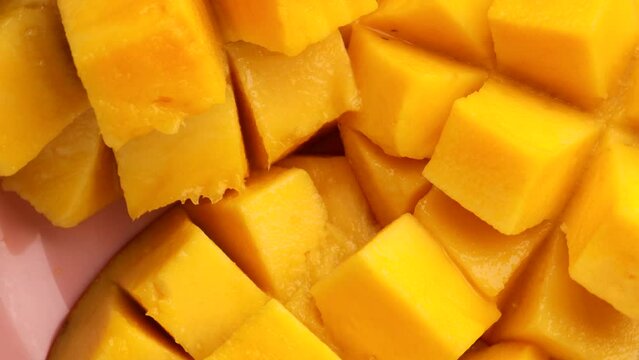 cream flowing through mango cube slices. Pouring heavy cream over juicy yellow Mango Fruit