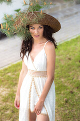 Beautiful woman in white summer dress and straw hat in the garden