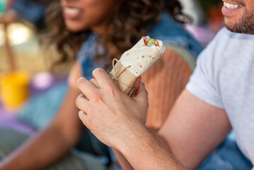 man is holding a burrito in his hand