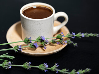 turkish coffee on dark background in white porcelain cup, wooden plate, traditional local refreshing drink, lavender flower