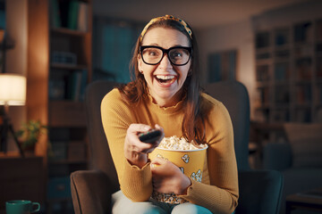 Expressive woman watching television and holding the remote control