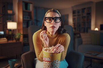 Woman watching a scary movie on TV