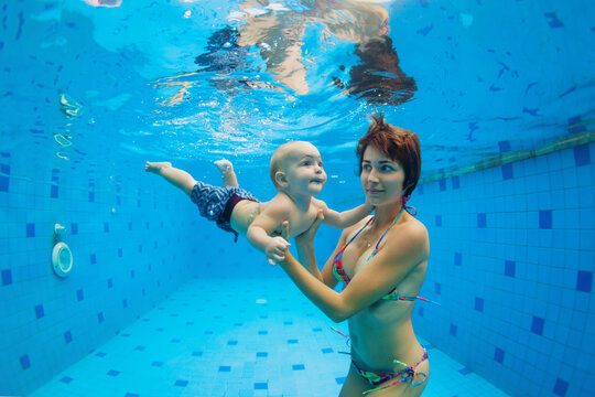 Happy family - mother, with baby boy swimming, diving underwater with fun in blue pool. Healthy lifestyle, active parents, people water sports activity on summer vacation with child