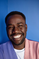 Obraz premium Vertical closeup portrait of black man smiling at camera in vibrant colors