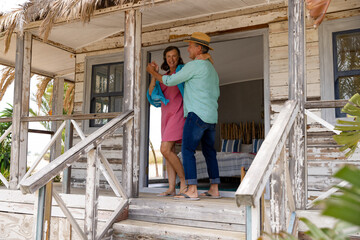 Fototapeta premium Happy caucasian senior couple wife dancing cheerfully on balcony outside wooden cottage