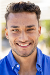 Obraz premium Close-up portrait of handsome caucasian young man with brown eyes smiling and looking at camera